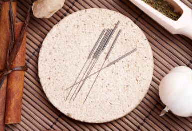 acupuncture needles on a stone plate with herbs