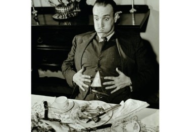 A person at a dinner table expressing that they are very full