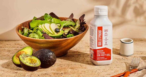 mct oil next to a bowl of lettuce and an avacado on the side