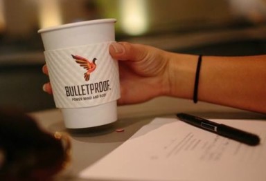 A hand holding a paper cup of coffee