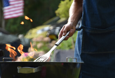 male figure using a grill with the American flag in the background