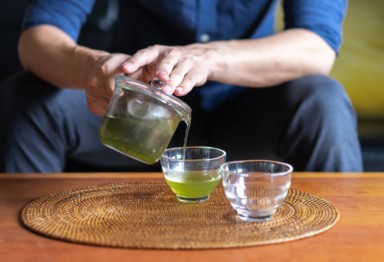Man pouring green tea into a mug.