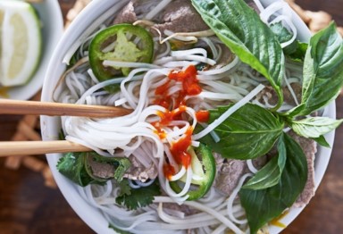 Eating bowl of pho with chopsticks