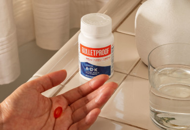 A person gets ready to consume a Bulletproof Vitamins A-D-K pill.