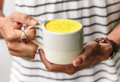 Hands holding a mug of yellow-tinted drink