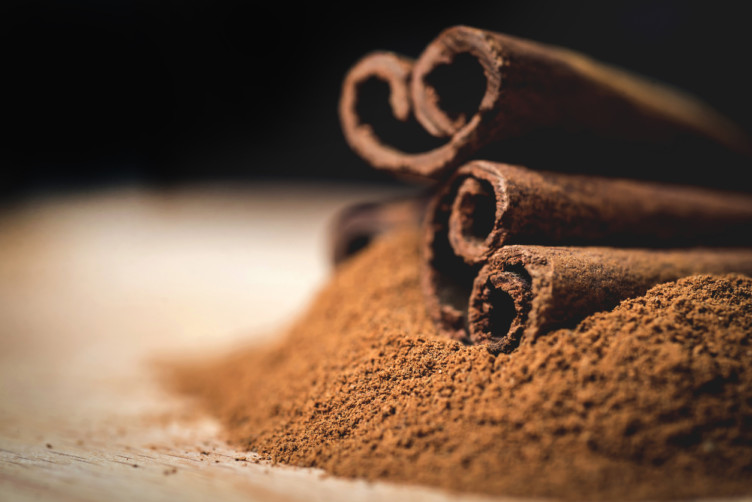 Cinnamon sticks with cinnamon powder on wooden background,