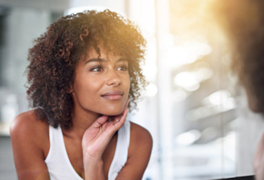 Woman looking at skin in mirror