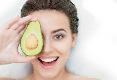 Woman holding an avocado over her eye