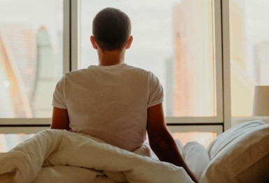 A person in bed looking out their window