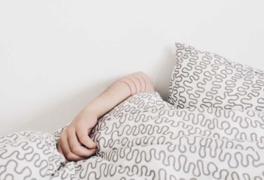 Person covered with gray blanket in bed