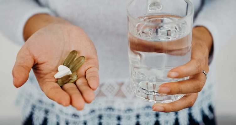 Person holding pills and glass of water