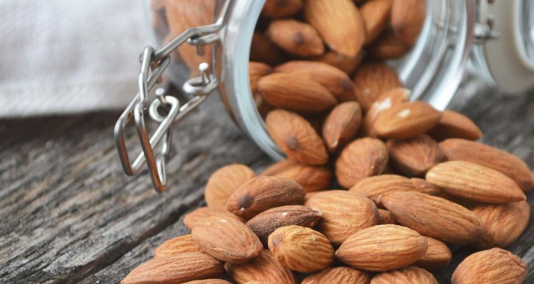 A jar of almonds spilling out on a table
