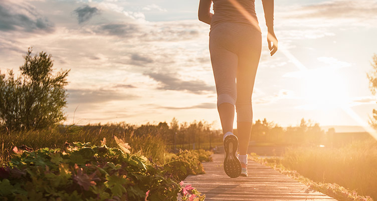 Woman jogging on trail in sunshine