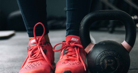 Personne portant des chaussures rouges à côté d'une kettlebell