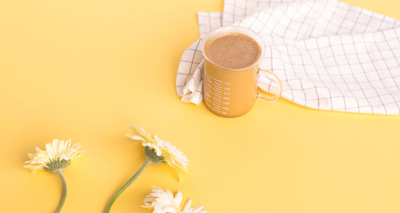 Cup of Bulletproof Coffee on yellow background