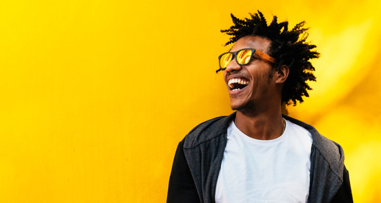 Man smiling in front of yellow background