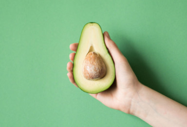 Hand holding avocado sliced in half