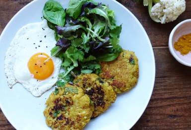A plate of cauliflower fritters with an egg and a side salad