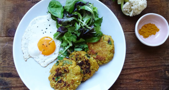 A plate of cauliflower fritters with an egg and a side salad