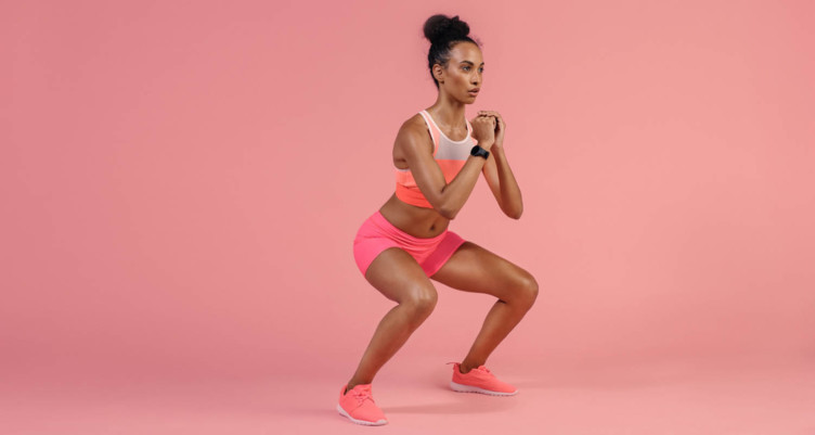 Woman holding squat in front of pink background