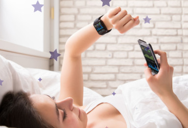 Woman looking at sleep tracker in bed