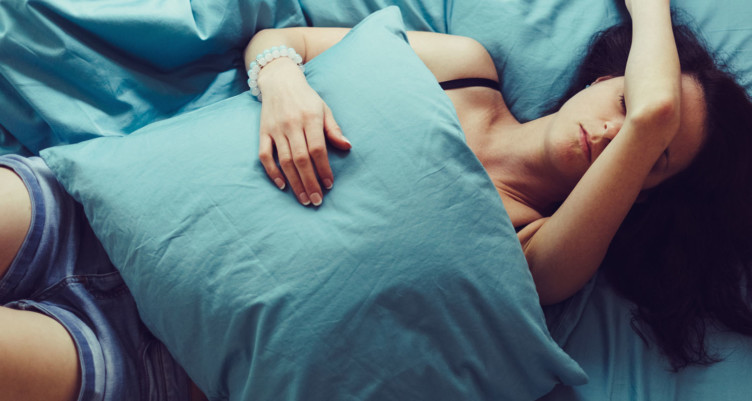 Woman on bed with pillow over stomach
