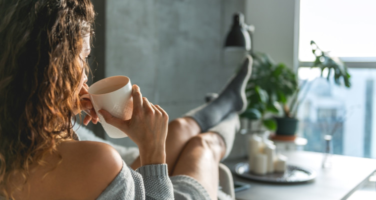 Woman sipping coffee while reclining in socks