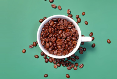 Cup of coffee beans on teal background