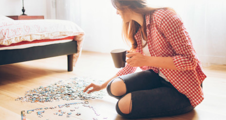 Nő a padlón kirakott puzzle-t fejezi be