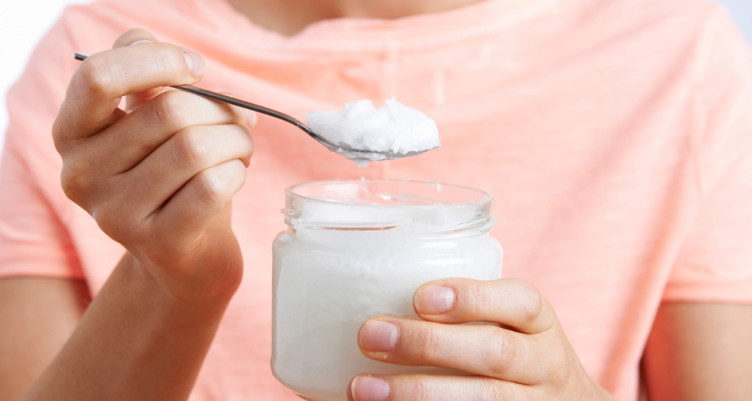 Woman holding spoonful of coconut oil