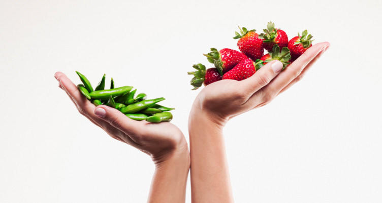 Two hands holding strawberries and snap peas