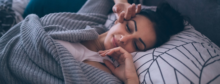 Woman stretching while wearing gray sweater in bed