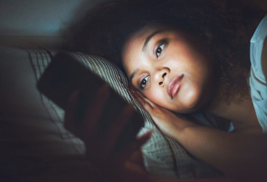 Woman in bed looking at her cell phone screen