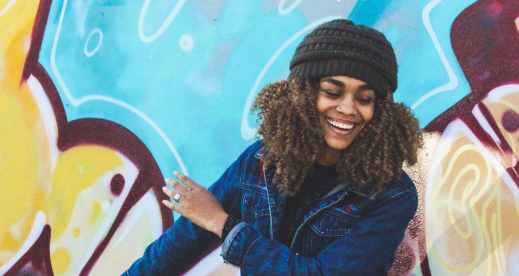 Woman wearing beanie smiling in front of colorful wall
