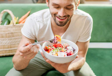 Man eating colorful food while sitting at green bench