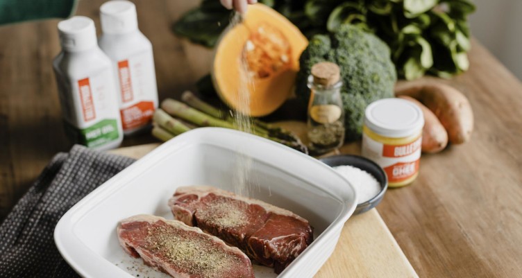 A person seasoning steak with Bulletproof products for cooking