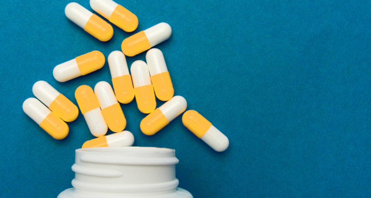 Bottle of yellow pills on blue background