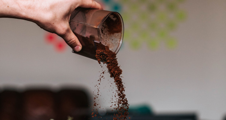 Hand pouring coffee grounds