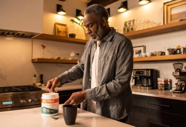Man scooping Bulletproof Innerfuel Prebiotic into coffee mug in a kitchen setting