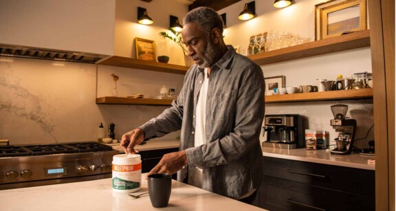 Man scooping Bulletproof Innerfuel Prebiotic into coffee mug in a kitchen setting