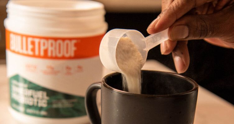 Close up of a hand scooping Bulletproof Innerfuel Prebiotic into coffee mug