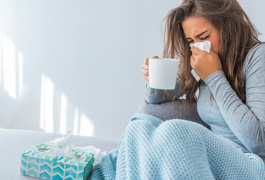 Woman blowing nose and drinking tea