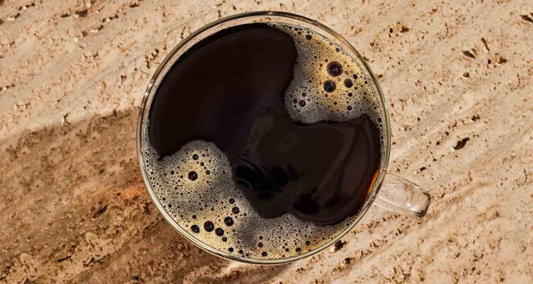 Overhead point of view of a black coffee on travertine countertop