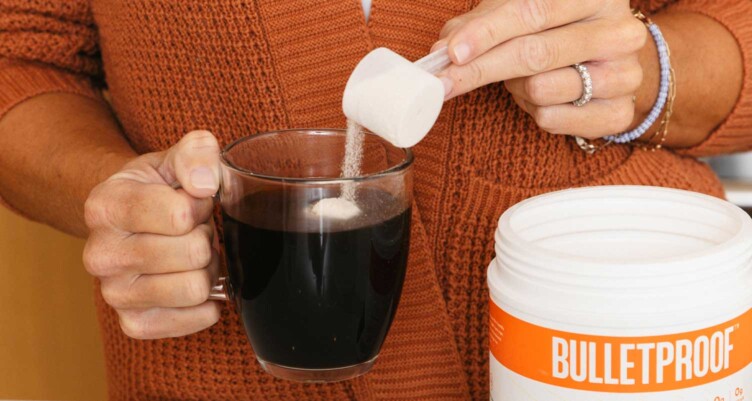 hands adding white powder into black coffee