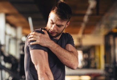Man clutching his shoulder in the gym.