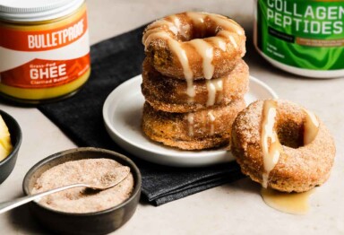 Stack of apple cider donuts with Bulletproof Grass-Fed Ghee and Bulletproof Unflavored Collagen Peptides in the background.