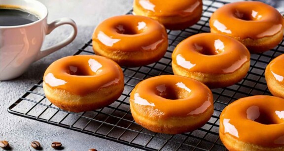 Espresso donuts on a cooling rack next to a mug of coffee.