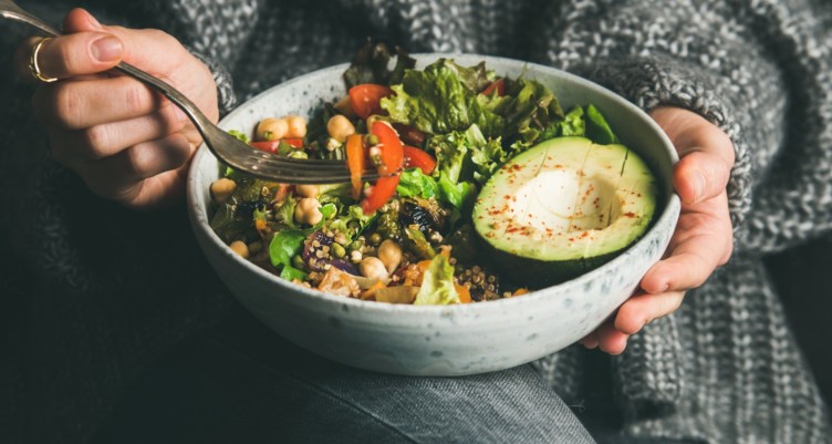 Person eating a salad bowl with avocado