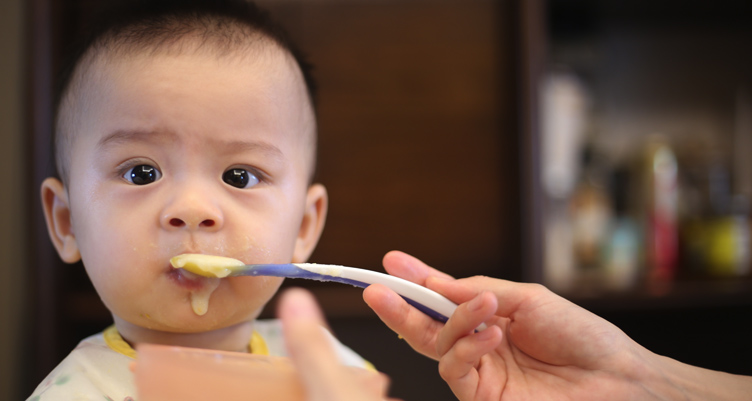 Baby eating food off spoon