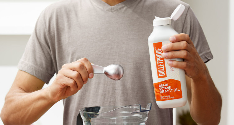 A man pours one serving of Bulletproof Brain Octane C8 MCT Oil into a blender.